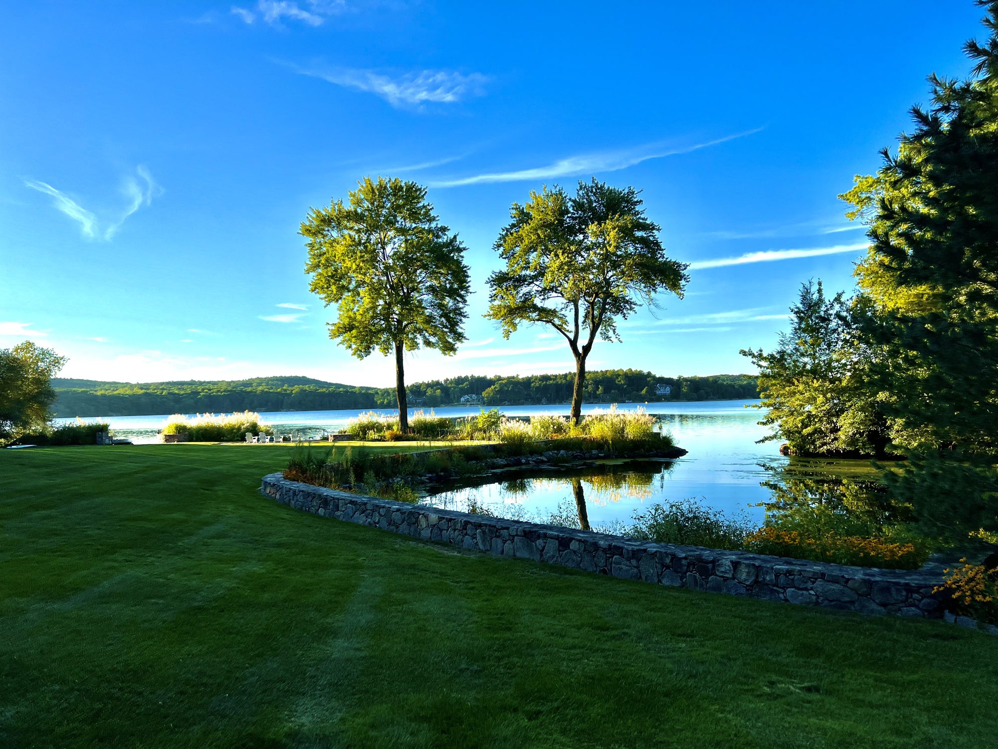 The manicured grounds and stone wall along the lake